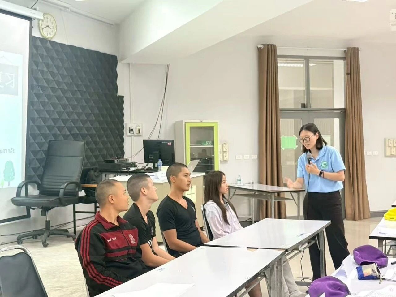 ครูยืนสอนผู้เรียนที่นั่งเรียงแถวในห้อง