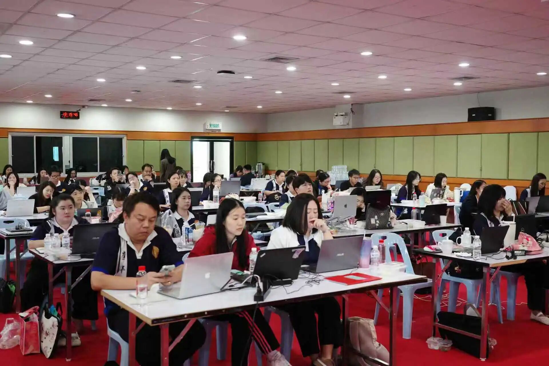 ครูผู้เข้าอบรมนั่งทำงานกับคอมพิวเตอร์โน้ตบุ๊กเต็มห้องประชุม